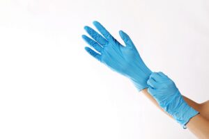 A Hand Pulling Blue Gloves on Another Hand
