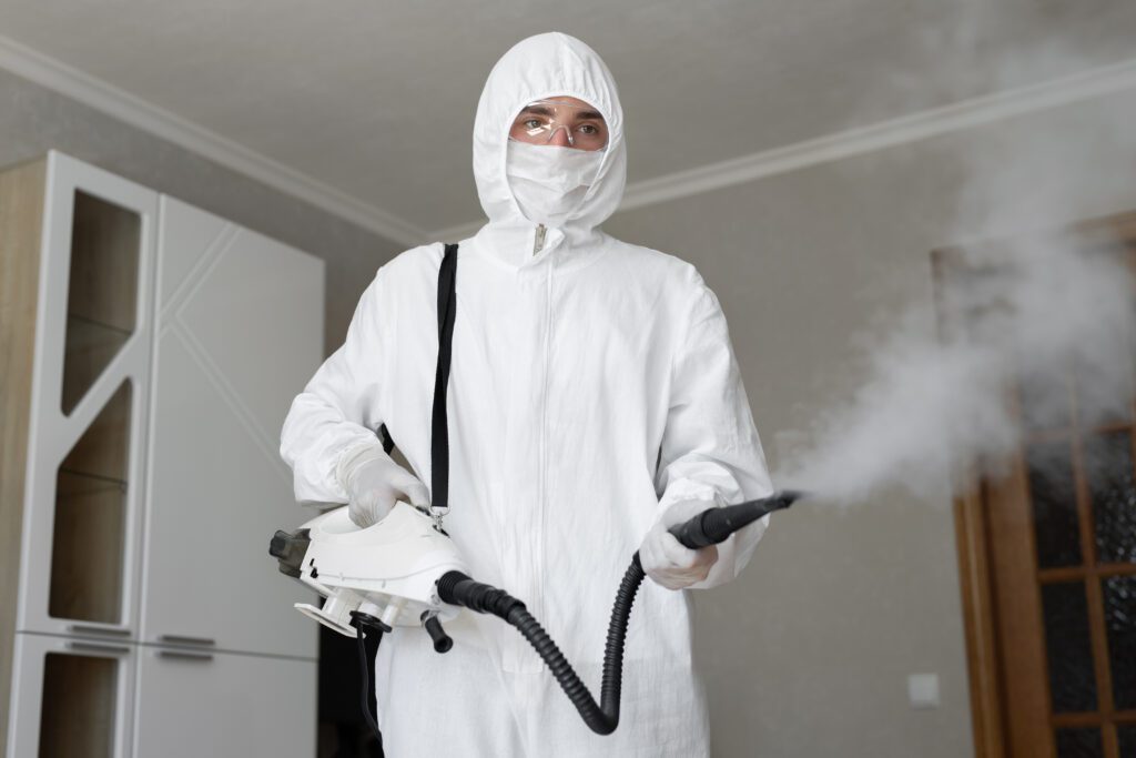 A Man in a White Overall Holding a Pest Spray in Hand